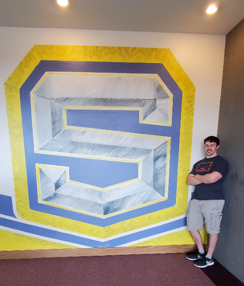 Student Stands In Front of a Mural